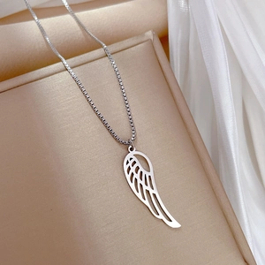 Detail of silver hollow wing pendant on box chain inside a beige jewelry gift box