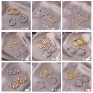 Collection of nine gold and silver hoop earrings displayed on grey silk fabric