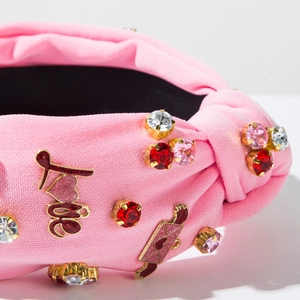 Dettaglio fascia rosa in maglia con strass di cristallo e ricamo della scritta Love