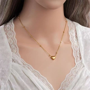 Elegant gold titanium steel heart necklace with small beads worn by a model on neck