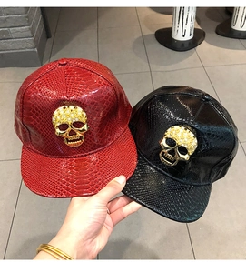 Detail of red and black faux snakeskin snapback hats with rhinestone gold skull buckle