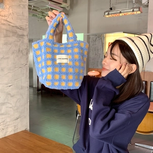 Detailed close-up of soft blue and yellow checkered lamb wool tote bag held by model