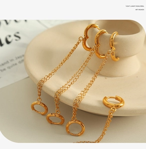 Detail of gold hoop earrings with long chains on a white ceramic jewelry stand