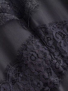 Close-up of elegant black floral eyelash lace detail and smooth satin fabric texture
