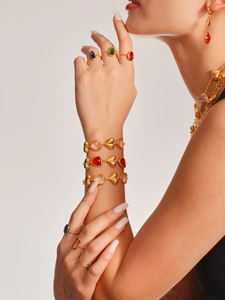 Detalle del conjunto de joyas de corazón dorado con piedras de colores en modelo femenina