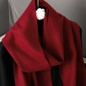 Detailed close-up of soft red cashmere-like scarf texture with elegant white flower accent