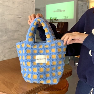 Detail of plush lamb wool tote bag featuring blue and yellow checkerboard pattern and logo