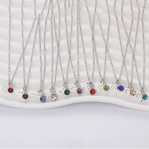 Stainless steel zodiac necklaces with colorful birthstones on white ceramic tray