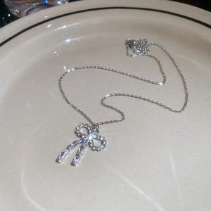 Macro shot of a silver bow necklace with sparkling diamonds on a ceramic plate