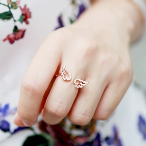 Close-up of rose gold double wing open ring with sparkling white crystal accents