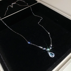 Macro shot of a teardrop-shaped light blue stone necklace on a black velvet box