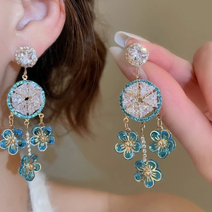 Close-up of zircon flower tassel earrings with blue enamel petals and gold plating
