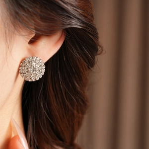 Gros plan de boucles d'oreilles rondes argentées avec strass pavés portées par un mannequin