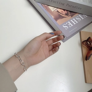 Detail view of silver S925 sterling silver wavy link bracelet worn on woman's wrist