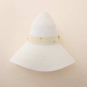 Close-up of handwoven white straw hat featuring a beige ribbon with gold and silver beads