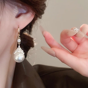 Gros plan de la boucle d'oreille en perle dorée avec détails en zircone sur modèle
