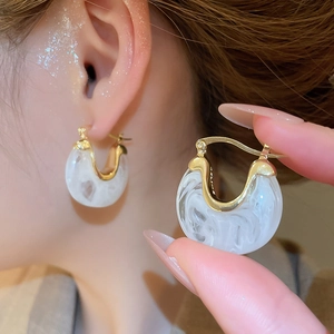 Détail de boucles d'oreilles vintage en U, métal doré et résine à texture marbre blanc