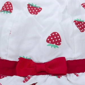 Dettaglio di cappello da sole bianco con stampe di fragole e fiocco rosso decorativo