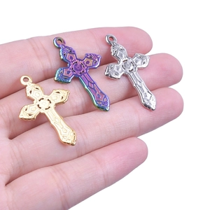 Textured stainless steel cross pendants in gold, silver and rainbow colors on hand