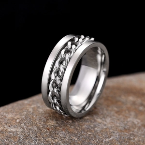 Macro shot of silver spinner ring with rotating Cuban chain on a textured stone