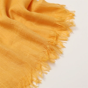 Close-up of yellow cotton linen scarf showing detailed fabric texture and tassel fringe