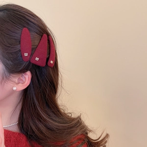 Detail of dark red plush triangle hair clips with gold B letter on model brown hair