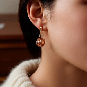 Detail showing vintage golden hollow ball drop earrings on model with warm knitwear
