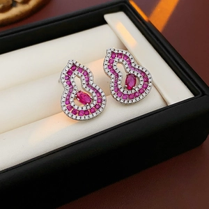 Macro shot of silver stud earrings with pink zircon in a hollow gourd-shaped design