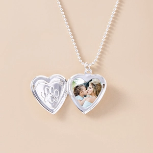 Detailed open silver heart locket showing paw print engraving and photo space