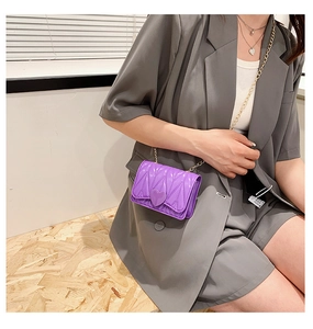 Detail of purple heart-shaped silicone mini crossbody bag with gold chain strap on model