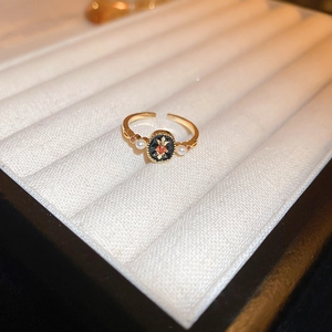 Macro shot of gold dragon ring with black oval gem and red crystal on jewelry box