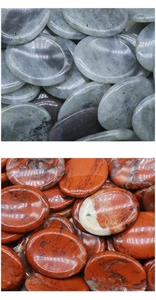 Macro shot of polished oval guasha stones in natural grey-green and reddish-brown textures