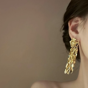 Détail de boucles d'oreilles longues rose dorée à franges métalliques portées