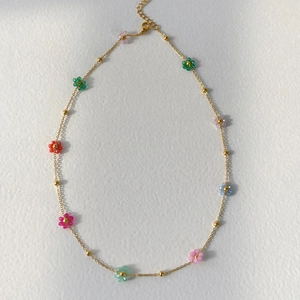 Detail of a gold-plated necklace featuring colorful floral beads and adjustable lobster clasp