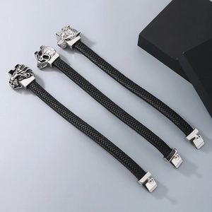 Detail of woven black leather bracelets featuring silver lion, skull and wolf charms