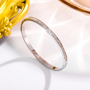 Elegant silver stainless steel bangle featuring emerald-cut cubic zirconia on silk background