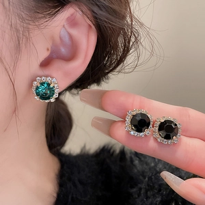 Gros plan sur les boucles d'oreilles halo avec pierres vertes et noires serties