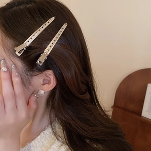 Gros plan d'un modèle portant des pinces à cheveux dorées et des boucles d'oreilles