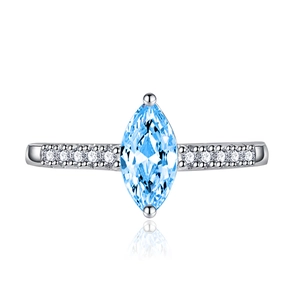 Macro detail of marquise-cut light blue topaz ring with silver band and side zircon stones