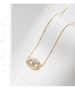Macro detail of gold evil eye pendant with blue center stone and baguette-cut zircons