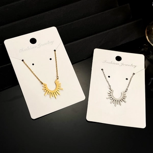 Gros plan de pendentifs soleil dorés et argentés présentés sur des cartes bijoux blanches