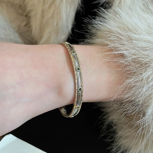 Gros plan sur un bracelet bicolore vintage avec pierres émeraudes vertes et détails