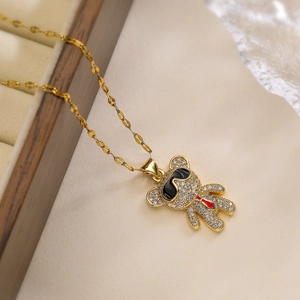 Golden bear pendant necklace with sparkling rhinestones and red tie on beige velvet