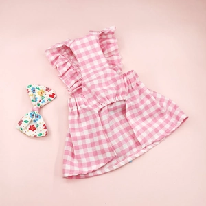 Close-up of pink plaid pet dress with matching floral bow headband on a pink background