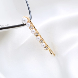 Elegant gold pearl hair clip with rhinestones displayed on white silk fabric background