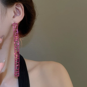 Dettaglio di modella che indossa orecchini a nappa rosa con strass scintillanti