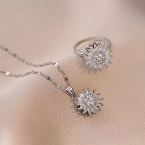 Macro shot of silver sunflower jewelry set with sparkling rhinestones on pink silk