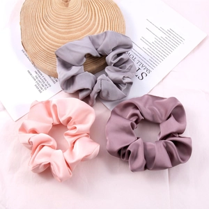 Three high-quality silk satin scrunchies in gray, pink, and violet with glossy texture