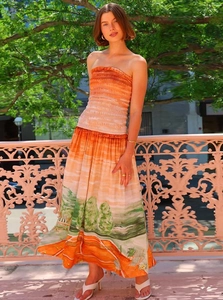 Detail of smocked bodice and vibrant orange landscape print on strapless maxi dress