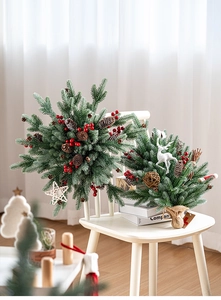 Close-up of mini Christmas tree and wreath with red berries, pinecones on white chair